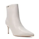 Botas de caña baja marca Bottero, color marfil, con punta fina y taco aguja. Presentan un diseño minimalista con cierre lateral y detalle de placa metálica con logo en la parte superior.