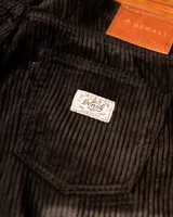 Pantalon de pana negra con textura acanalada, corte recto y diseño de cinco bolsillos.