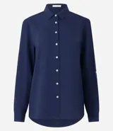 Camisa de manga larga color verde lima, con cuello camisero y botonadura frontal. Presenta un dobladillo trasero más largo que el delantero.