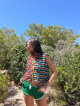 Chaleco tejido a mano en crochet con hilado 100% algodón, con diseño de ondas horizontales en colores azul, rojo y verde. Tiene tiras para atar en el frente.