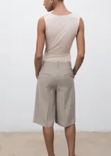 Body sin mangas de color beige, con escote drapeado y diseño entallado. Confeccionado en tejido elástico con tirantes anchos.