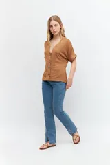 Remera marrón de tejido liso, con escote en V, mangas cortas y cierre frontal con botones.