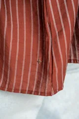 Blusa de manga larga con diseño a rayas verticales, cuello redondo con pequeña abertura frontal abotonada y mangas con puños elásticos.