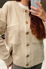 Saco tejido de lana color arena con cuello redondo, cierre con botones marrones y bolsillos frontales. Diseñado y hecho en Uruguay.