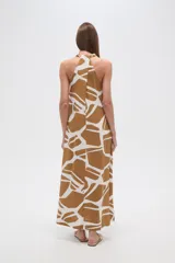 Vestido largo de corte holgado con estampado geométrico en tonos verde oliva y blanco. Presenta cuello en V, diseño sin mangas y bolsillos laterales.