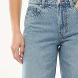 Jeans de mezclilla en tono azul medio con tiro alto y corte flare, con aberturas laterales en el dobladillo inferior.