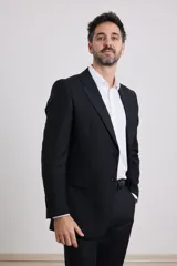 Traje de corte clásico compuesto por saco de dos botones y pantalón de vestir a juego. El saco presenta solapas tradicionales y bolsillos con solapa, mientras que el pantalón tiene un corte recto y formal.