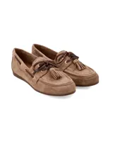 Mocasín náutico de cuero gamuza color camel, con detalles de costuras pespunteadas, cordones de cuero oscuro entrelazados con ojales metálicos dorados y borlas decorativas en el empeine.