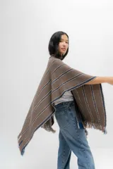 Ruana marrón con rayas horizontales azules y blancas, y flecos en los bordes.