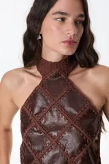 Top halter negro confeccionado con una mezcla de cuero y tejido artesanal, con diseño geométrico de rombos unidos por costuras de crochet y dobladillo en punta.