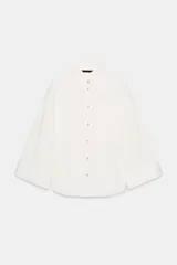 Camisa oversize de color blanco, con cuello solapa, manga ancha por debajo del codo y bolsillo delantero de plastrón. Cierre frontal con botones.