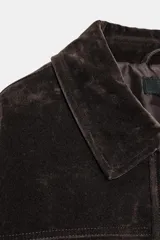 Chaqueta estilo bomber de corte oversize en color marrón oscuro, confeccionada con acabado aterciopelado. Presenta un cuello de solapa con detalle de pelo sintético desmontable, cierre frontal oculto con cremallera y botones a presión, bolsillos delanteros con solapa y bajo elástico.