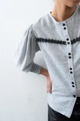 Blusa estampada en blanco y negro, con cuello redondo y mangas globo de puños elastizados largos. Presenta tiras ajustables en los laterales.