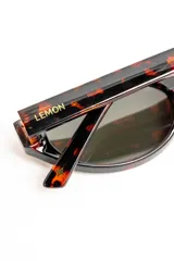 Lentes de sol con armazón ovalado de acetato negro y micas oscuras.