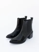 Bota tipo Chelsea de cuero negro con acabado brillante, punta fina y taco cuadrado.