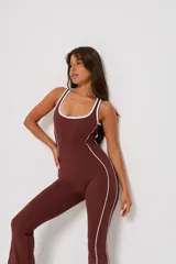 Mono deportivo de una pieza color marrón, con diseño ajustado, escote redondo y tirantes anchos. Presenta líneas laterales blancas en contraste que recorren la prenda desde el escote hasta el ruedo.
