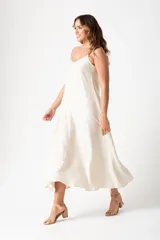 Vestido largo color crudo, de corte recto y breteles finos.