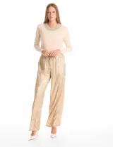 Pantalón de corte wide leg en tejido laminado metalizado color gris. Presenta pretina ancha elastizada con lazo de ajuste y bolsillos delanteros.