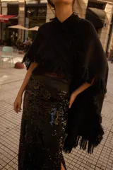 Pollera larga de lentejuelas negras con diseño de tajo lateral profundo. Presenta una cintura alta con banda lisa y corte recto que se ajusta a la silueta.
