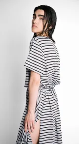 Vestido largo de corte recto, con cuello bote, mangas cortas y abertura lateral. Diseño a rayas horizontales en blanco y negro. Incluye lazo en la cintura.