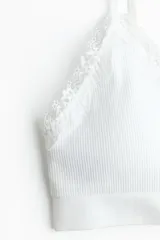 Soutien tipo Bralette color blanco de punto suave y diseño seamless, con breteles ajustables y ribete de encaje en los bordes. Copas con relleno extraíble, sin aros ni cierre.