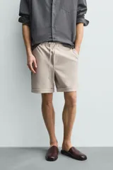 Bermuda regular fit de tejido elástico color blanco, con cintura elástica ajustable mediante cordón, bolsillos delanteros y bolsillos traseros de vivo.