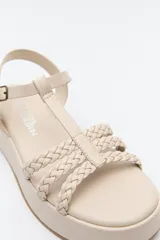 Sandalia de plataforma color marrón con tiras trenzadas y pulsera con hebilla.