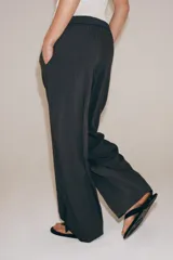 Pantalón de tiro medio con diseño de pierna ancha y estampado de rayas verticales. Cuenta con cintura elástica ajustable mediante cordones y bolsillos laterales ocultos en la costura, con aberturas en el bajo.