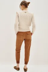 Pantalón tipo babucha de gabardina elastizada, color negro, con cintura elástica ajustable mediante cordón, puños en los tobillos, bolsillos diagonales frontales y bolsillos traseros con solapa y botón.