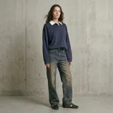 Jean de corte recto y tiro medio con efecto de lavado desgastado en tonos azul y marrón. Presenta ruedo desflecado y cierre frontal con botón y cremallera.