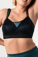 Bralette deportivo negro con detalles en verde, confeccionado en jersey y tela de faja de alta contención. Posee breteles anchos acolchados regulables, faja reforzada en bajobusto y escote extra alto.