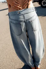 Jeans negro de tiro medio con corte balloon fit, diseño de cinco bolsillos y bajo acabado en puño con abertura y botón.