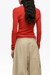 Pantalón cargo beige de tiro bajo y corte ancho, con múltiples bolsillos con solapa en los laterales de las piernas y cierre frontal con botón y cremallera oculta.