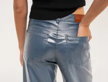 Pantalón de jean elastizado azul con terminación metalizada, corte wide leg, tiro medio, cierre delantero con botón, bolsillos laterales y traseros.