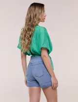 Short de denim blanco tiro alto, estilo pull-on con cintura elástica ancha, bolsillos delanteros y traseros, y dobladillo en las piernas.