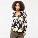 Blusa de corte fluido con estampado floral en contraste, cuello camisero, cierre frontal de botones y mangas tres cuartos.