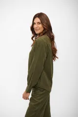 Camisa de manga larga con cuello clásico y cierre frontal de botones, confeccionada en tejido con textura tipo gamuza.