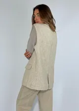 Chaleco largo color crudo con solapas, sin mangas y cierre con dos botones.