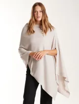 Poncho tejido de punto con diseño asimétrico y caída fluida, ideal para superponer sobre otras prendas.