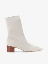 Bota tipo media de punto color beige con caña media, punta fina y taco cuadrado de madera de altura baja.