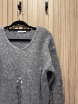 Sweater gris de punto con escote en V y detalle de lentejuelas bordadas.