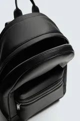 Mochila de diseño minimalista en color negro con acabado grabado. Cuenta con un compartimento principal con cierre de cremallera, un bolsillo frontal con cierre y un compartimento posterior acolchado para dispositivos electrónicos. Incluye asa de mano superior y dos asas de hombro ajustables.
