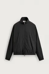 Cazadora bomber de corte relajado confeccionada en tejido técnico color negro. Presenta cuello subido, manga larga amplia, bolsillos de vivo en cadera, acabados elásticos y cierre frontal con cremallera de doble dirección.