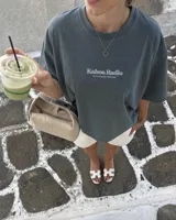 Remera oversize negra con diseño gráfico en la espalda que incluye la inscripción "Kaboa Radio" y un personaje ilustrado, de corte amplio y mangas cortas.