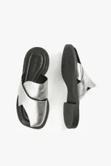 Sandalias planas de cuero color blanco hueso, con dos tiras anchas cruzadas en la parte superior y diseño minimalista.