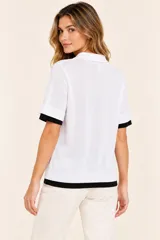 Remera polo de punto color blanco con detalles en negro en el cuello, la botonera, los puños y el ruedo, de manga corta y calce clásico.