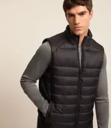 Chaleco masculino deportivo tipo puffer, color negro, con cuello alto, gajos acolchados y cierre delantero con cremallera.