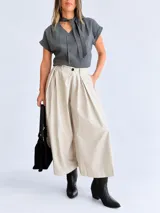 Pantalón palazzo color beige, de tiro alto y calce amplio, con pinzas frontales y bolsillos laterales.