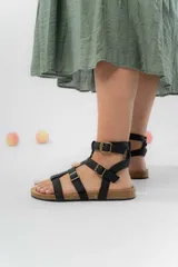 Sandalia gladiadora color marrón claro de cuero sintético, con múltiples tiras y hebillas metálicas ajustables. Base de corcho y plantilla anatómica forrada en eco-cuero.