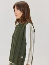 Chaleco de paño con diseño bicolor, frente en color negro y espalda en color marrón con textura de espiga. Presenta un maxi bordado de hoja en la parte posterior y detalles de tejido en los bordes.